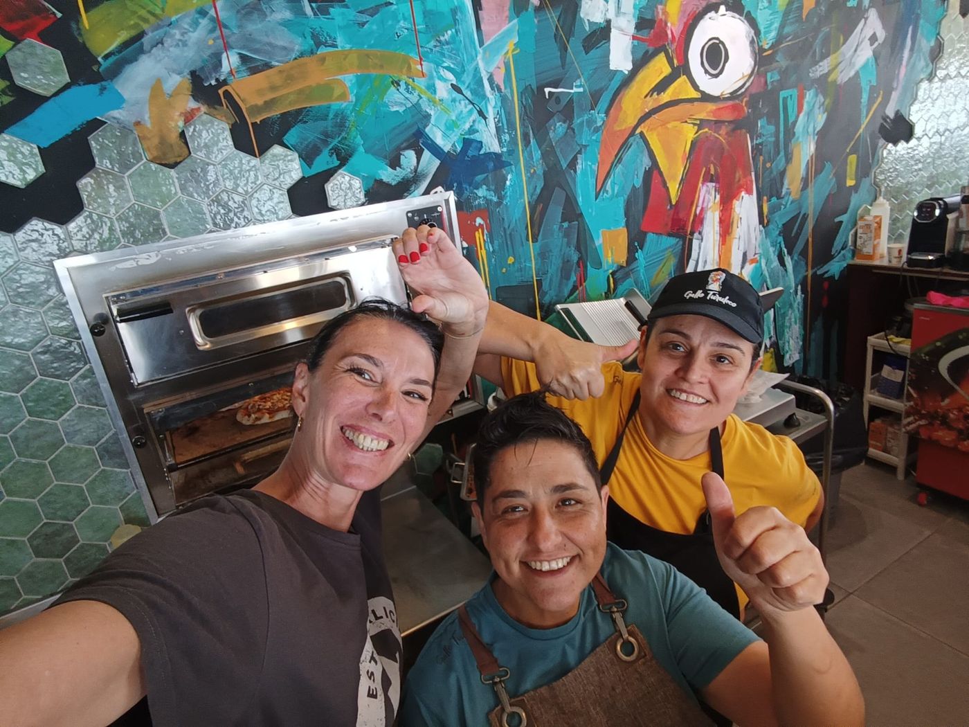 Kuimby, Elisa y Sonia frente al mural del gallo
