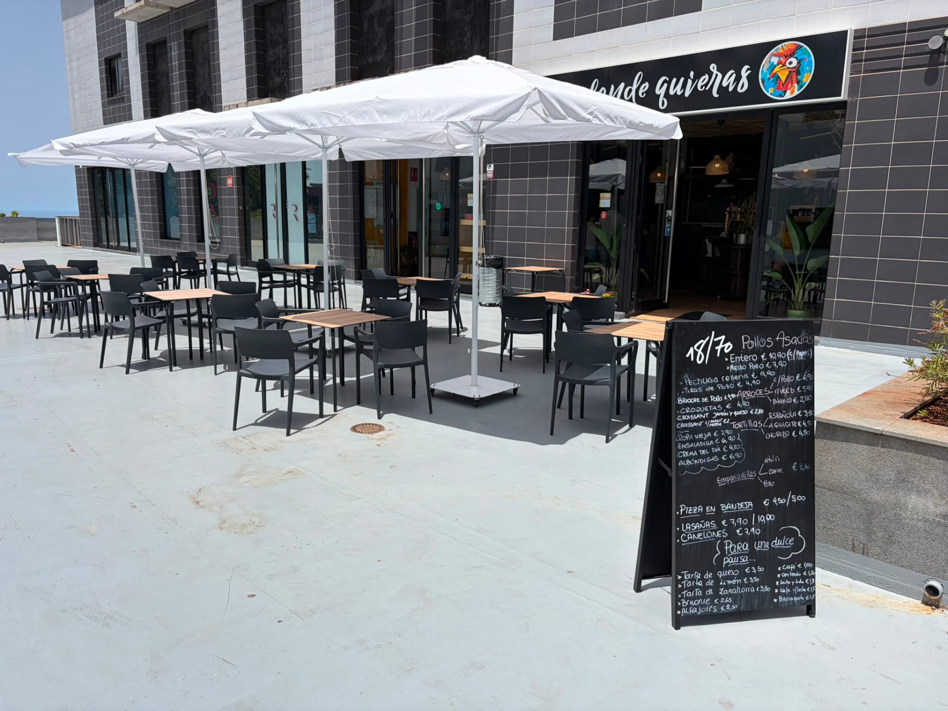 Terraza de El Gallo Turuleco con sombrillas blancas y mesas al aire libre