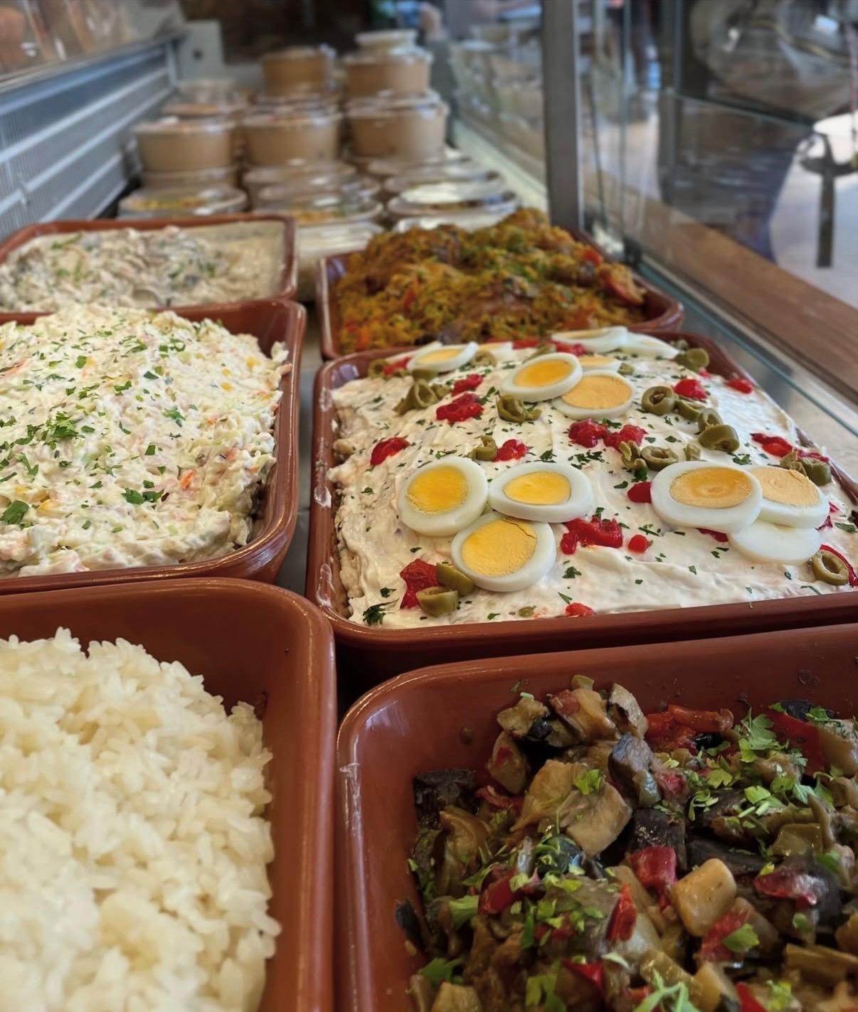 Bandejas de ensaladilla, guiso de garbanzos y arroz blanco en la vitrina